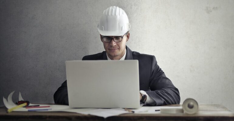 Man with a construction helmet, with a laptop.