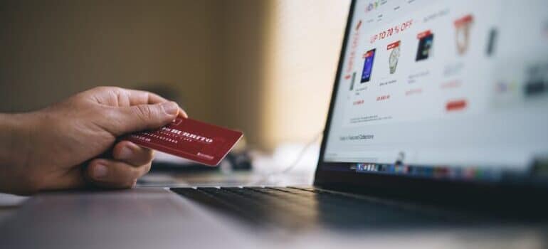 A person holding a credit card and looking at an eCommerce website on a laptop.