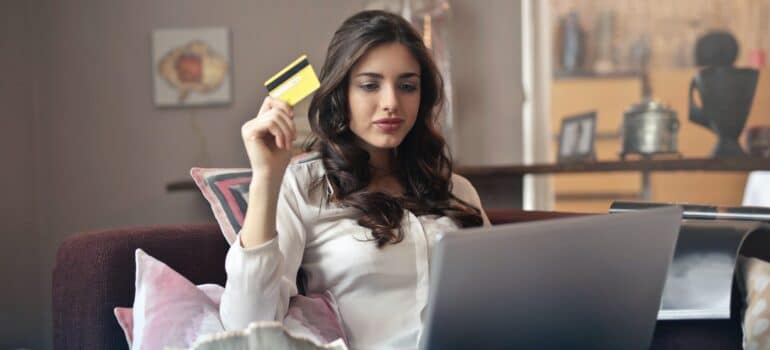 A woman using a credit card while looking at a laptop.