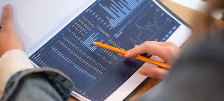 Person pointing at data and graphs with pencil.