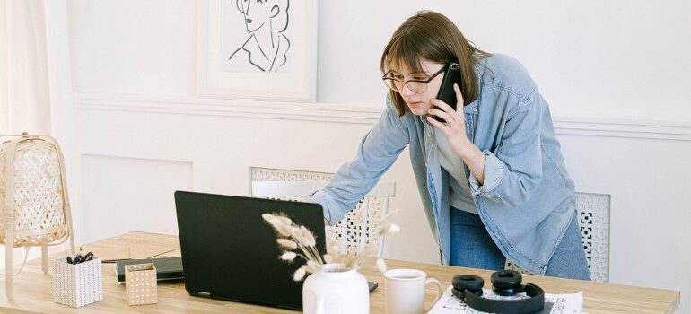 A woman answering emails while talking on her phone, showing the value of effective email management tips.