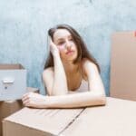 A woman feeling distressed, surrounded by boxes.