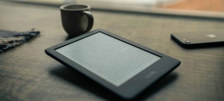 An ebook reader next to a cup of coffee.