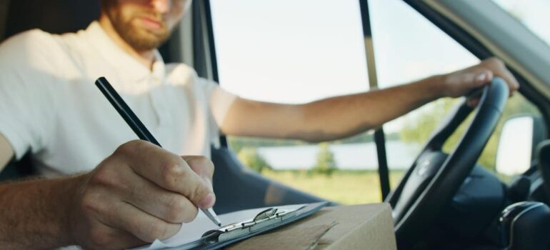 man writing on paper inside of a moving van