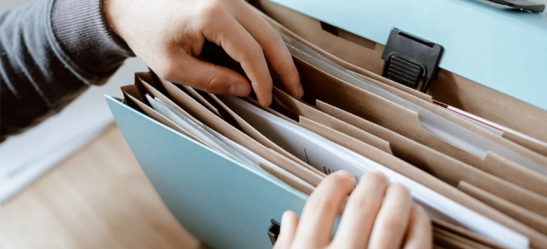 A close-up of a person sorting through a light blue document folder.
