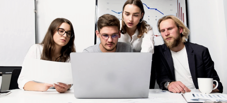 A group of people in an office looking at a laptop screen.
