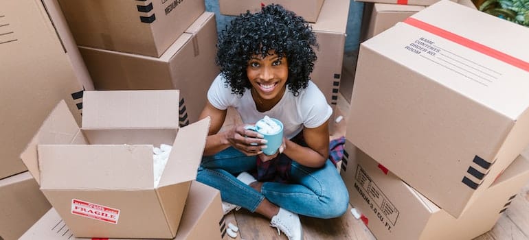 A smiling woman surrounded by moving boxes.